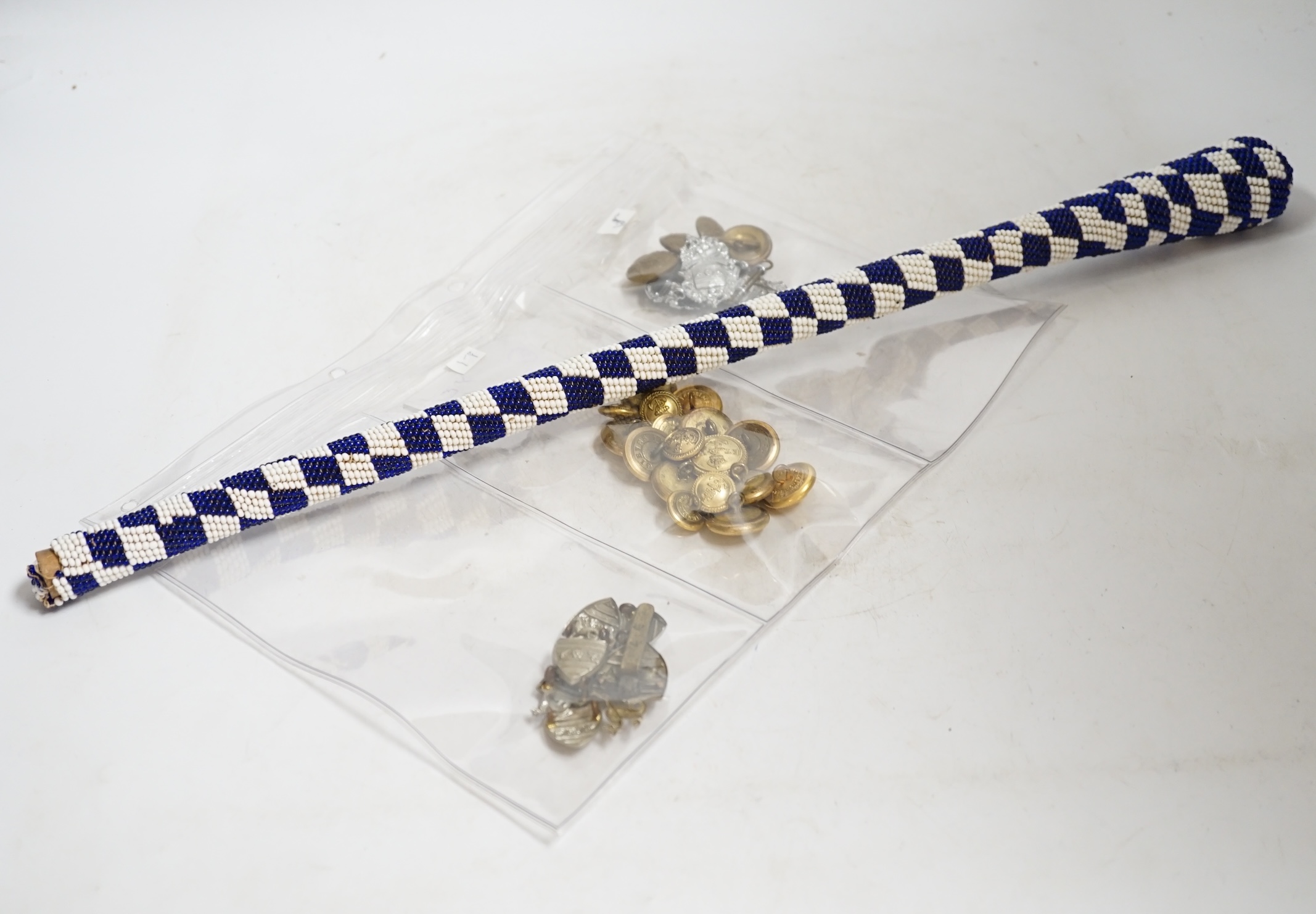 A collection of Police badges and buttons, including to Eastbourne Borough Police helmet plates, Eastbourne Fire Brigade uniform buttons, Royal Navy buttons, a whistle, etc. together with a batten decorated with beadwork